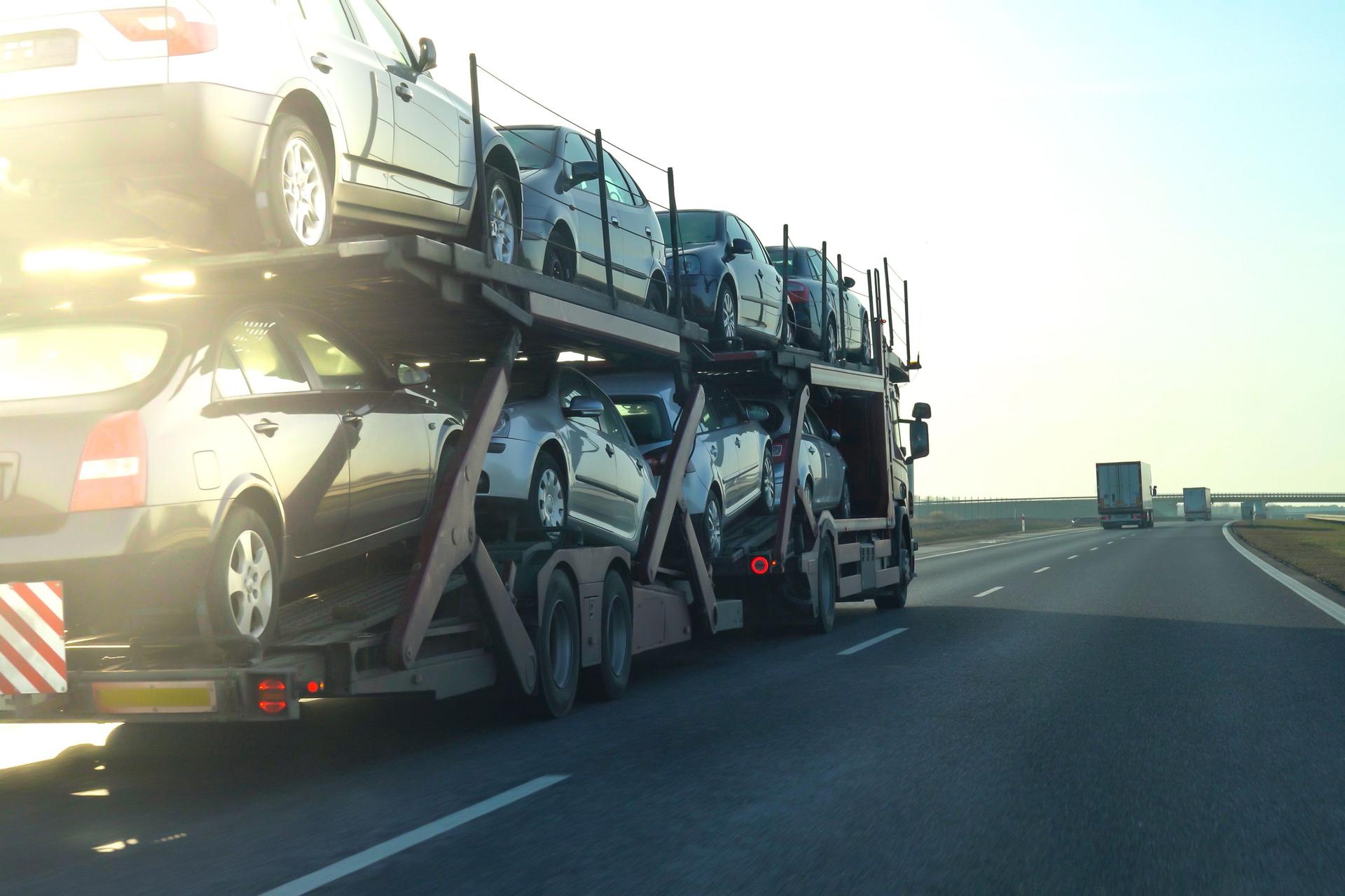 Car transporter trailer loaded with many cars on a highway, motion blur effect.