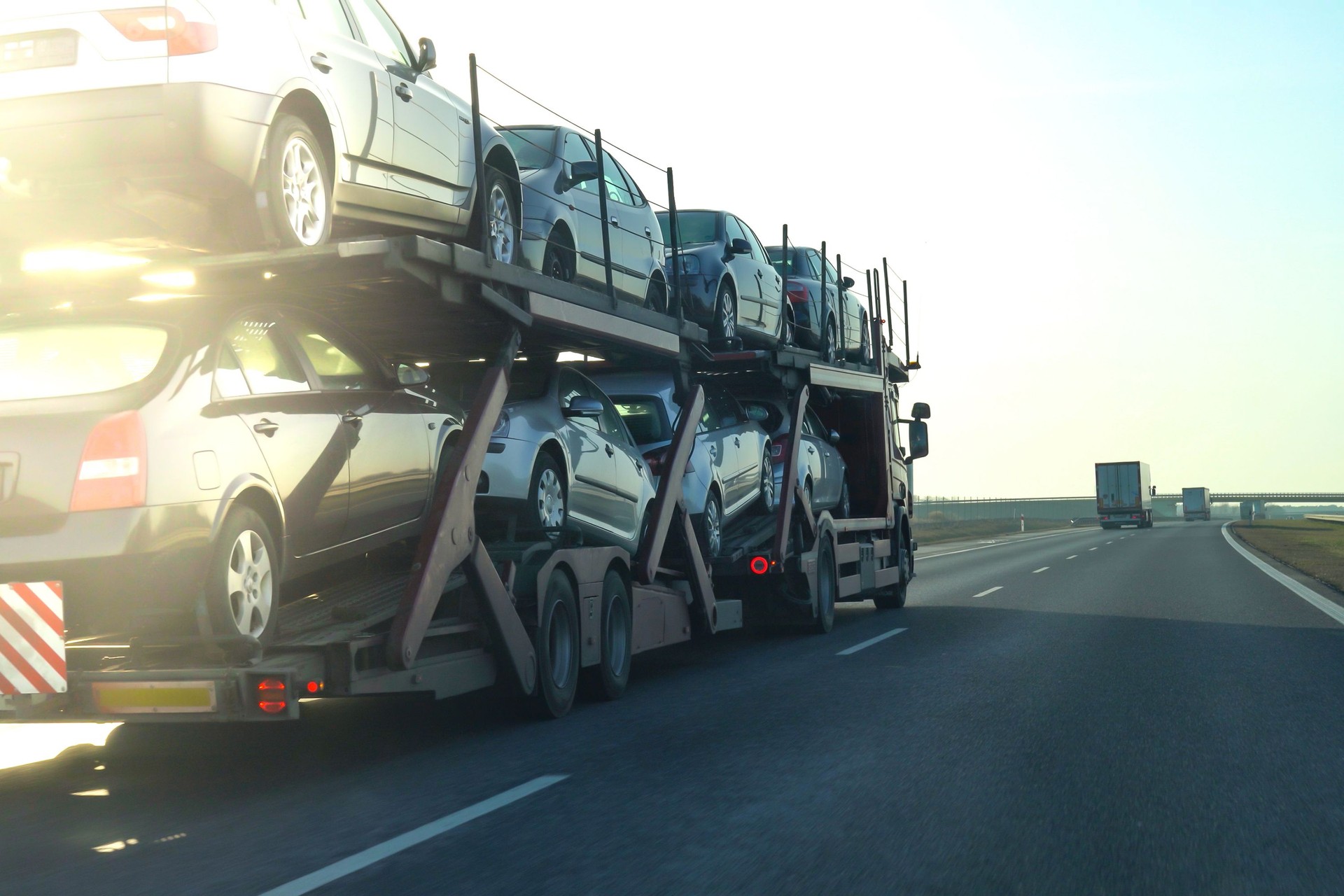 Car transporter trailer loaded with many cars on a highway, motion blur effect.