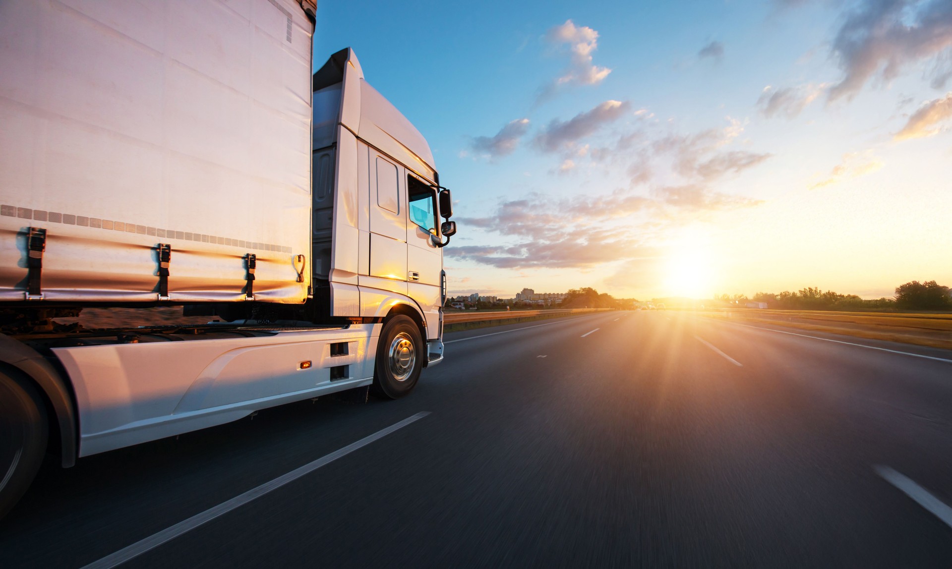 European truck driving on the asphalt road in rural landscape at sunset